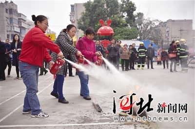 广源路社区居民正在练习用灭火器喷灭大火。